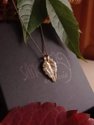 Colgante de cerámica y oro con forma de hoja.