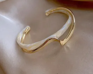 Pulsera rígida dorada y beige nacarado.