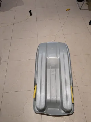 Trineo de plástico gris con asas amarillas