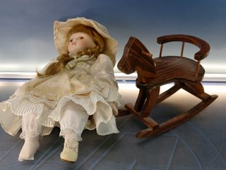 Esther. Bambola di porcellana seduta su altalena, cavallo di legno