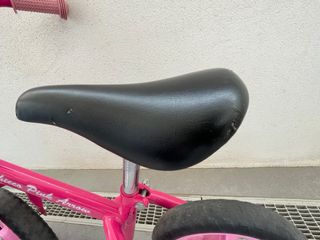 Bicicleta infantil rosa sin pedales con casco