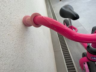 Bicicleta infantil rosa sin pedales con casco