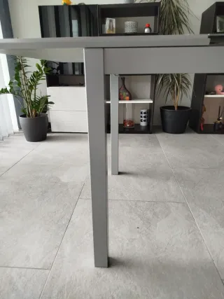 Mesa de comedor gris metálica y tapa de cristal.