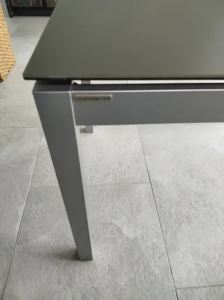 Mesa de comedor gris metálica y tapa de cristal.