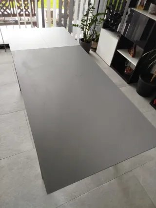 Mesa de comedor gris metálica y tapa de cristal.