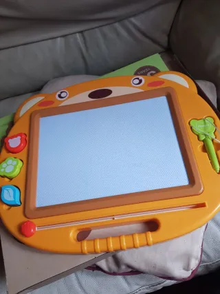 Pizarra magnética infantil con imágenes y puntero.