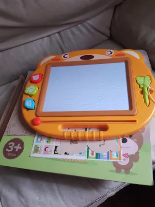 Pizarra magnética infantil con imágenes y puntero.