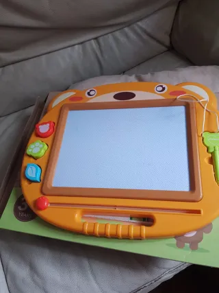 Pizarra magnética infantil con imágenes y puntero.