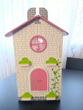 Casa de muñecas rosa con muebles.