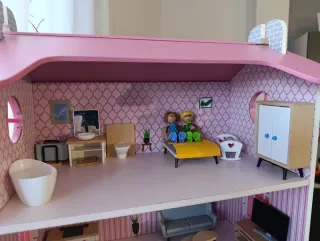 Casa de muñecas rosa con muebles.