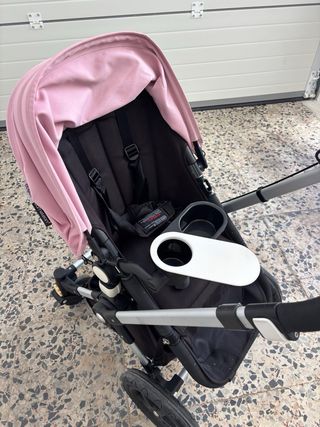 Cochecito de bebé rosa con plástico protector