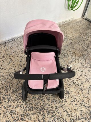 Cochecito de bebé rosa con plástico protector