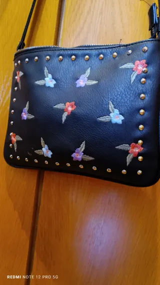 Bolso negro con flores bordadas y tachuelas