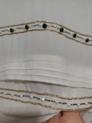 Blusa blanca con detalles dorados.