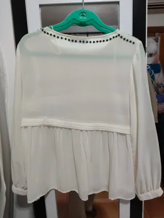 Blusa blanca con detalles dorados.