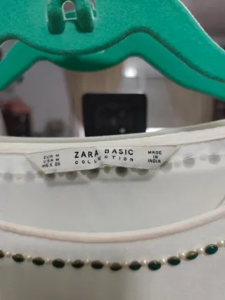 Blusa blanca con detalles dorados.