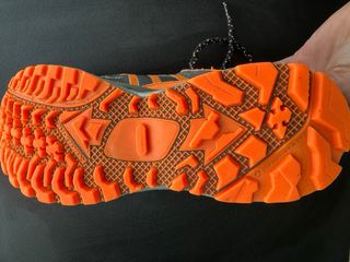 Zapatillas trail running grises y naranjas.