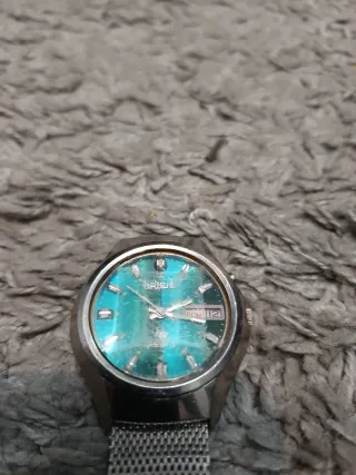 Reloj plateado con esfera turquesa