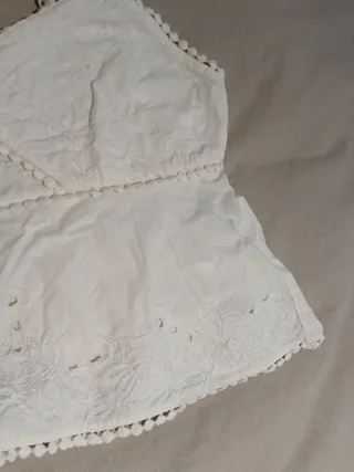 Top blanco con bordados y pompones