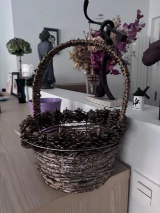 Cesta decorada con piñas y asa.