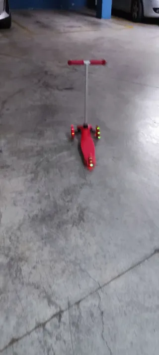 Patinete infantil rojo de tres ruedas con luces.