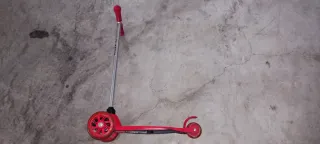 Patinete infantil rojo de tres ruedas con luces.