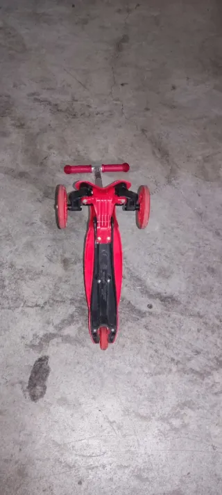 Patinete infantil rojo de tres ruedas con luces.