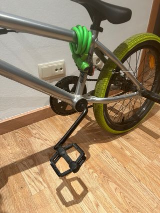 Bicicleta BMX plateada con ruedas verdes