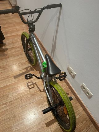 Bicicleta BMX plateada con ruedas verdes