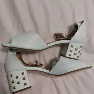 Zapatos blancos con tacón dorado y tachuelas