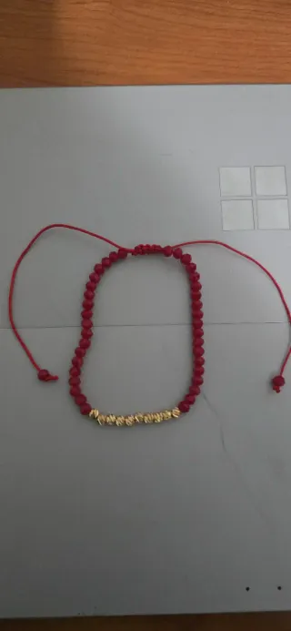 Pulsera roja con detalles dorados