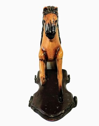 Antiguo caballo de madera sobre plataforma con ruedas de hierro.