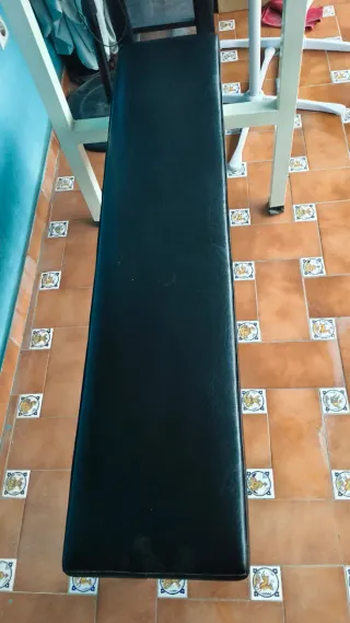 Banco de pesas incluido una mancuerna grande.