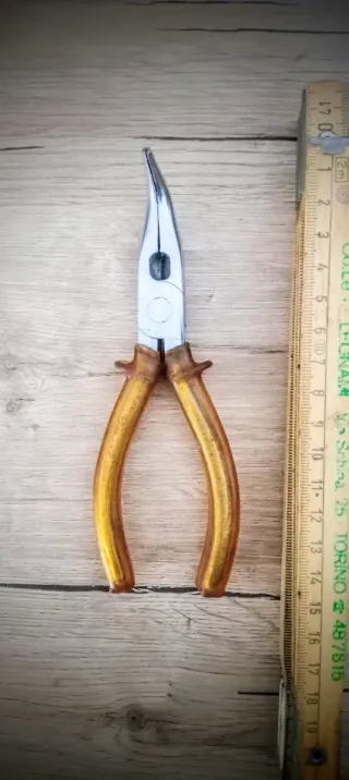 Pinza con becchi lunghi piegati e manico in gomma.