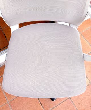 Silla de oficina giratoria beige con ruedas.