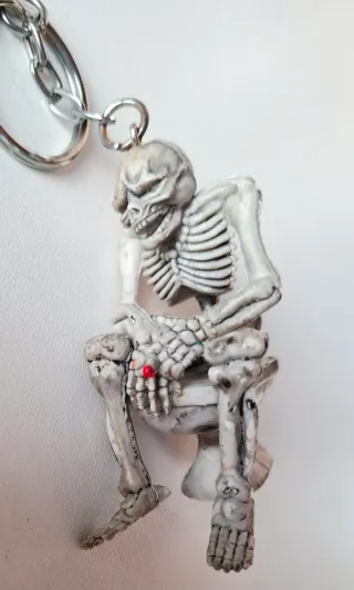 Llavero figura esqueleto fumando y cagando en WC