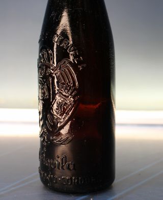 Botella antigua El Águila, ambar, con relieve.