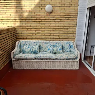 Sofá de mimbre blanco con cojines florales