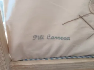 Mini cuna de madera con textiles.