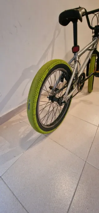 Bicicleta BMX plateada con ruedas verdes