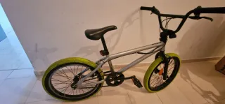 Bicicleta BMX plateada con ruedas verdes