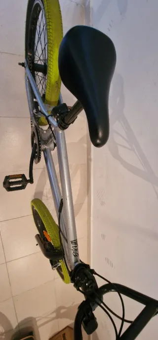 Bicicleta BMX plateada con ruedas verdes