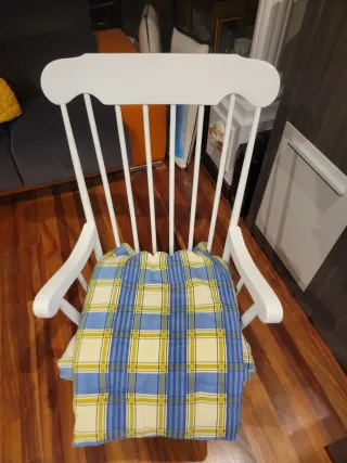 Due dondoli in legno bianco con cuscino. Cuscino a quadri in blu, giallo e bianco.