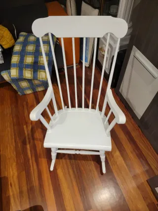 Due dondoli in legno bianco con cuscino. Cuscino a quadri in blu, giallo e bianco.