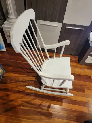 Due dondoli in legno bianco con cuscino. Cuscino a quadri in blu, giallo e bianco.