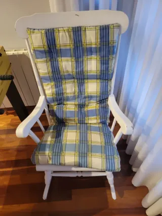 Due dondoli in legno bianco con cuscino. Cuscino a quadri in blu, giallo e bianco.