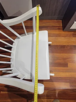 Due dondoli in legno bianco con cuscino. Cuscino a quadri in blu, giallo e bianco.
