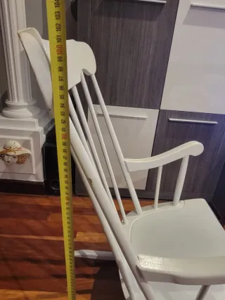 Due dondoli in legno bianco con cuscino. Cuscino a quadri in blu, giallo e bianco.