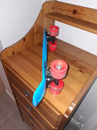 Monopatín azul con ruedas naranjas