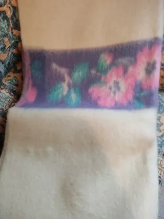 Manta de lana beige con flores moradas.